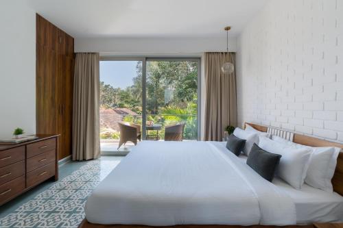 a bedroom with a large bed and a large window at La Olalian 2 & 3 BHK Designer Villas Near Anjuna Beach with Private Pool & Sun Deck & Garden in Anjuna