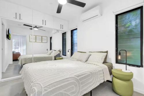 a white bedroom with two beds and a tv at Your Noosa HQ - modern apartment near everything! in Noosaville