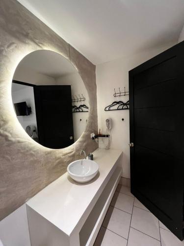 a bathroom with a sink and a round mirror at Grupo Hotelero Colibri in Panajachel