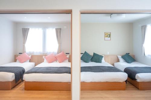 two beds in a room with a mirror at TKD HOUSE Furano 2 in Furano