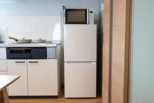 a white refrigerator with a microwave on top of it at TKD HOUSE Furano 2 in Furano