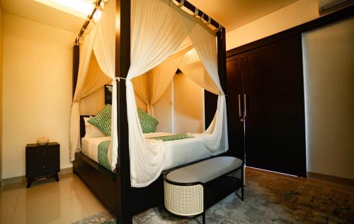 a bedroom with a canopy bed with a chair at Villa Mandee Guest House in Uluwatu