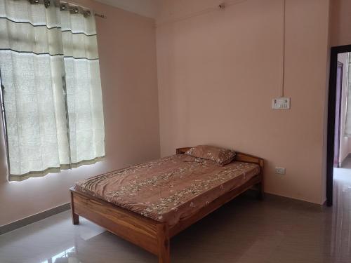 a small bed in a room with a window at The sanctuary homestay in Dimāpur