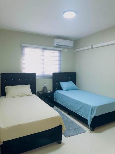 Un dormitorio con dos camas y una ventana. en Excelente Apartamento Completo Renta Carro Disponible, en La Viva