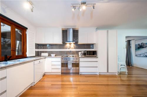 a kitchen with white cabinets and stainless steel appliances at Driftwood By Khove in Gold Coast