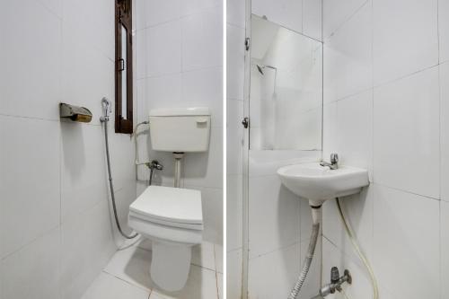 a white bathroom with a toilet and a sink at Super Collection O MP Nagar in Bhopal
