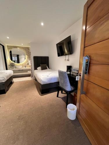 a hotel room with a bed and a desk and a tv at Grupo Hotelero Colibri in Panajachel