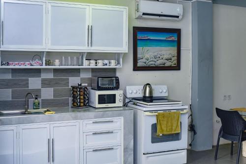 a kitchen with white cabinets and a white stove top oven at White House Cabin Cozy Retreat with Rustic Charm in Hermosa