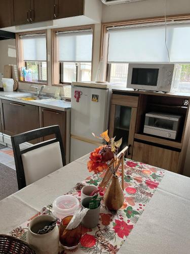 eine Küche mit einem Tisch mit Blumen darauf in der Unterkunft Guesthouse Hope in Hashima
