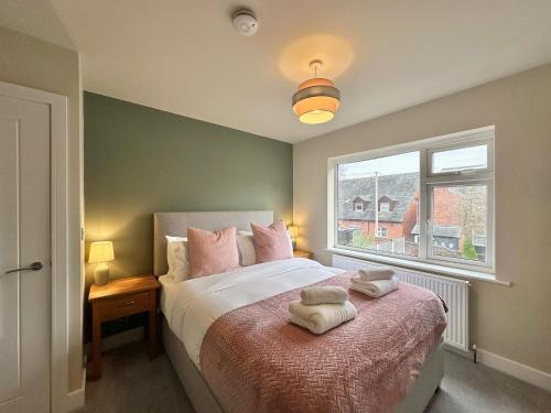 ヘレフォードにあるContemporary City Centre Apartments with Gardenのベッドとタオル2枚のある寝室