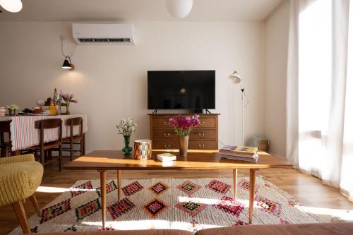 a living room with a table and a tv at Villa Hod Couples Suite with Mountain Views in ‘En Hod