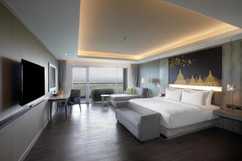 a hotel room with a bed and a couch and a television at Amaranta Prambanan Yogyakarta in Yogyakarta