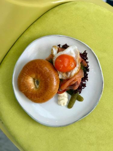 a white plate with a sandwich and a donut on a table at The Fig Lobby Bangkok in Bangkok