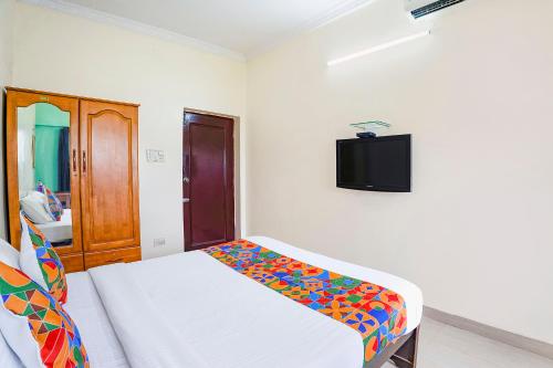 a bedroom with a bed and a tv on the wall at FabExpress Home Tree Service Apartment T Nagar - Near Mambalam Railway Station in Chennai