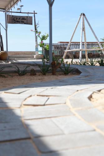 a stone walkway with a swing and a fence at EVA HUT Mui Ne Beach Hostel in Mui Ne