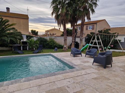 une piscine avec des chaises, une balançoire et une aire de jeux dans l'établissement Villa moderne de 220m2 avec piscine, Sérignan, à Sérignan