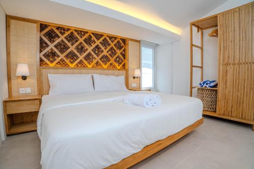 a bedroom with a large white bed with a window at Jiva Loft Style Villa in Canggu