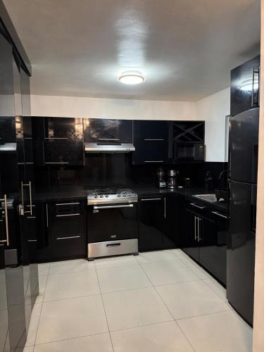 a kitchen with black cabinets and a stove top oven at Casa moderna y elegante en el corazón de Ensenada! in Ensenada