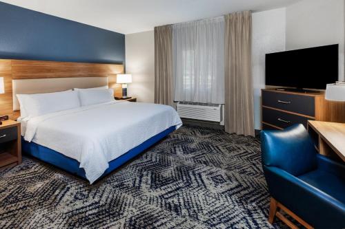 a hotel room with a bed and a television at Candlewood Suites Fayetteville by IHG in Fayetteville