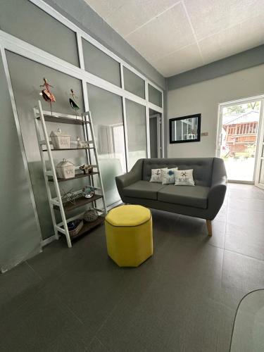a living room with a couch and a yellow stool at White House Cabin Cozy Retreat with Rustic Charm in Hermosa