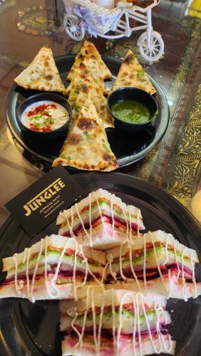 um prato de comida com fatias de pizza e molhos em Junglee Nest Holiday Home & Huts em Mahabaleshwar