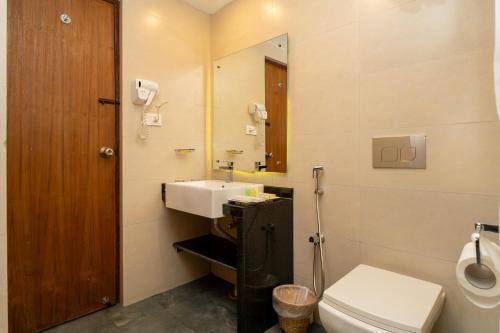 a bathroom with a sink and a toilet and a mirror at Bar Peepal Resort in Pokhara
