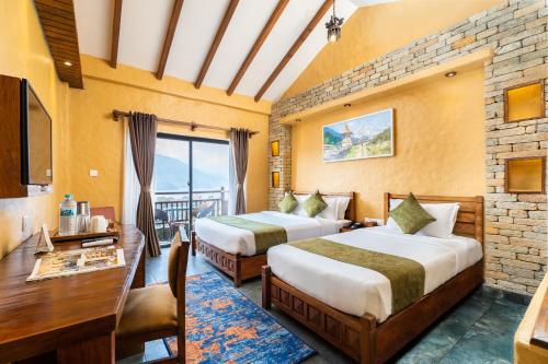 a hotel room with two beds and a desk at Bar Peepal Resort in Pokhara