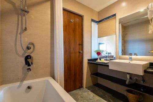 a bathroom with a white tub and a sink at Bar Peepal Resort in Pokhara