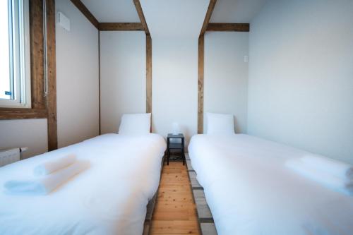 two beds in a small room with a window at Oreo Niseko 新築 ニセコ中心地 駐車場2台完備 in Kutchan