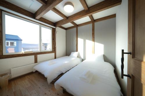 two beds in a room with a window at Oreo Niseko 新築 ニセコ中心地 駐車場2台完備 in Kutchan