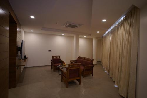 a waiting room with chairs and a table and curtains at Hotel Sastha Grand in Arcot