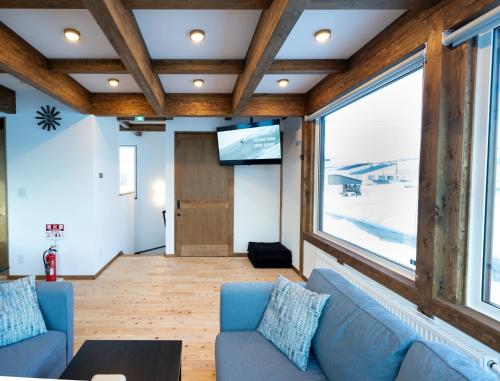 a living room with a blue couch and a large window at Oreo Niseko 新築 ニセコ中心地 駐車場2台完備 in Kutchan