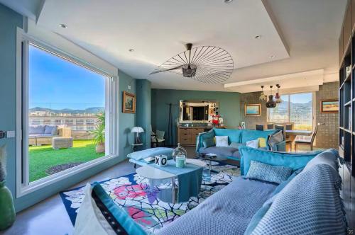 Elle comprend un salon doté d'un mobilier bleu et d'une grande fenêtre. dans l'établissement Appartement Prestige, Rooftop & Vue Panoramique, à Marseille