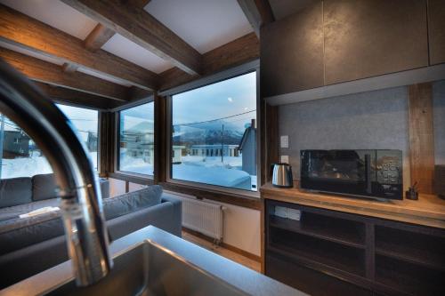 a kitchen with a living room with a fireplace and a tv at Oreo Niseko 新築 ニセコ中心地 駐車場2台完備 in Kutchan