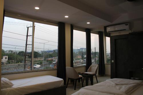 a hotel room with two beds and a large window at Hotel M Plaza Dhulagarh in Dhulagari