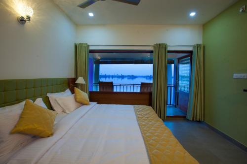 a bedroom with a large bed with a large window at Mira's PMC Lakeshore Resort in Alleppey