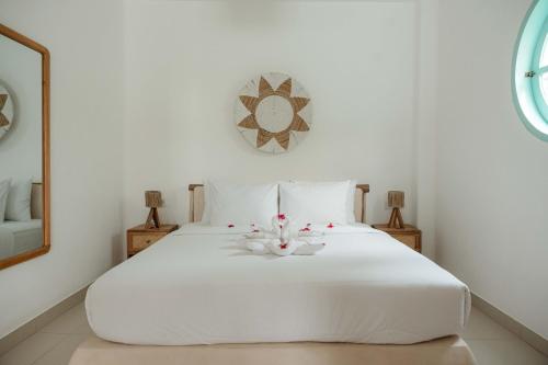 a bedroom with a white bed with flowers on it at Quma Boutique Hotel - Adults Only in Gili Trawangan