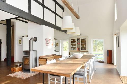 ein Esszimmer mit einem Holztisch und einem Holzofen in der Unterkunft Reet-Cottage Nahe der Ostsee in Süsel