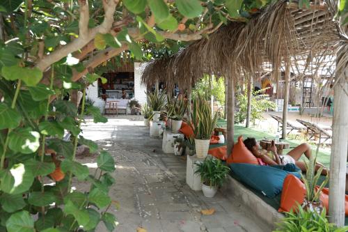 a person laying in a hammock under a straw umbrella at EVA HUT Mui Ne Beach Hostel in Mui Ne