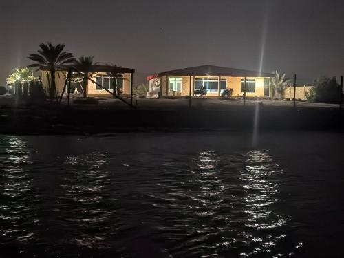 a house at night next to a body of water at NatureLand Beach Villa in Ḩabshān