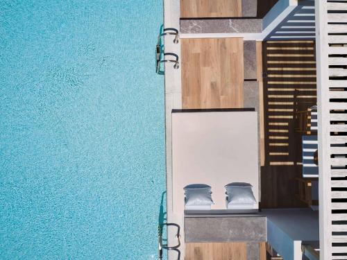 an overhead view of a swimming pool with two chairs at Grecotel LUXME White in Adelianos Kampos