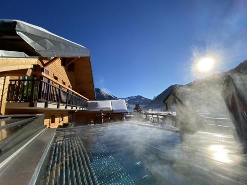 a building with a swimming pool with mountains in the background at Terra-Beka Lodge in La Chapelle-dʼAbondance
