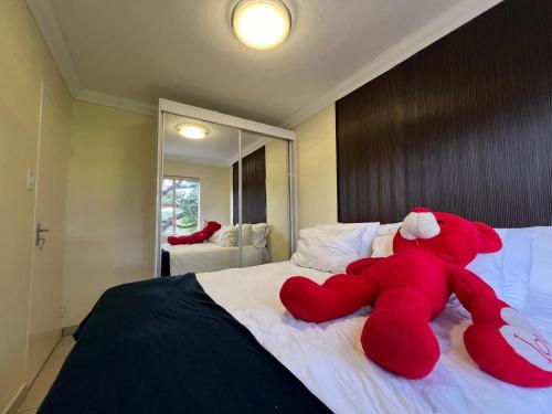 a red teddy bear laying on top of a bed at ROBIES MANs CAVE in Alberton