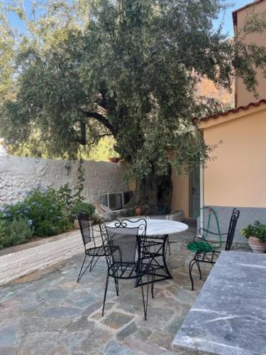 a patio with a table and chairs under a tree at 1867 Manor in Leonidio