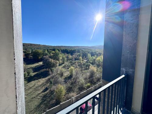 a room with a balcony with a view of a forest at Tsaghkadzor Kechi Heights Retreat - Luxe Family Apartment in Tsaghkadzor