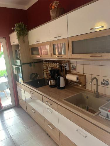 a kitchen with white cabinets and a sink at Tejfeles vendégház in Porva