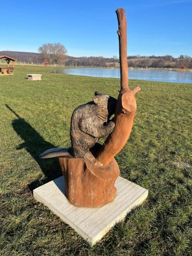 a statue of a bear sitting in a tree stump at Tejfeles vendégház in Porva