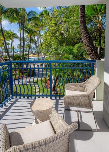 a balcony with chairs and a railing with palm trees at Hilton Aruba Caribbean Resort & Casino in Palm-Eagle Beach