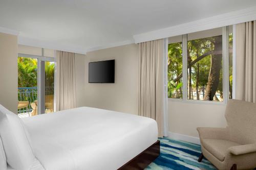 a white bedroom with a bed and a chair at Hilton Aruba Caribbean Resort & Casino in Palm-Eagle Beach
