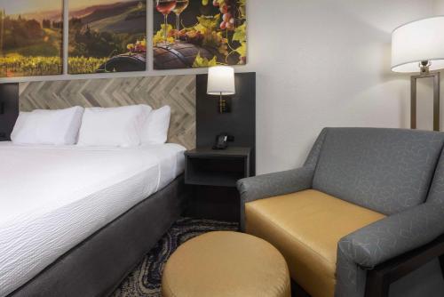a hotel room with a bed and a chair at Clarion Inn Biltmore Village in Asheville